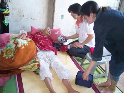 社區志工訪視長期臥病在床的老人，為其量血壓及轉介服務